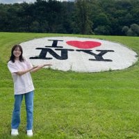 A person stands on grass and gestures toward a large