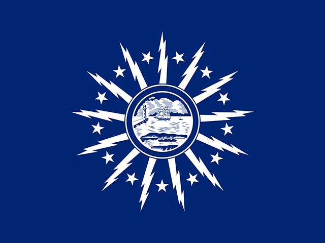 A blue flag featuring a central white seal with a ship, surrounded by radiating white lightning bolts and stars.